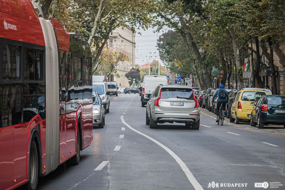 Troli és autók haladnak, mellettük egy kerékpáros