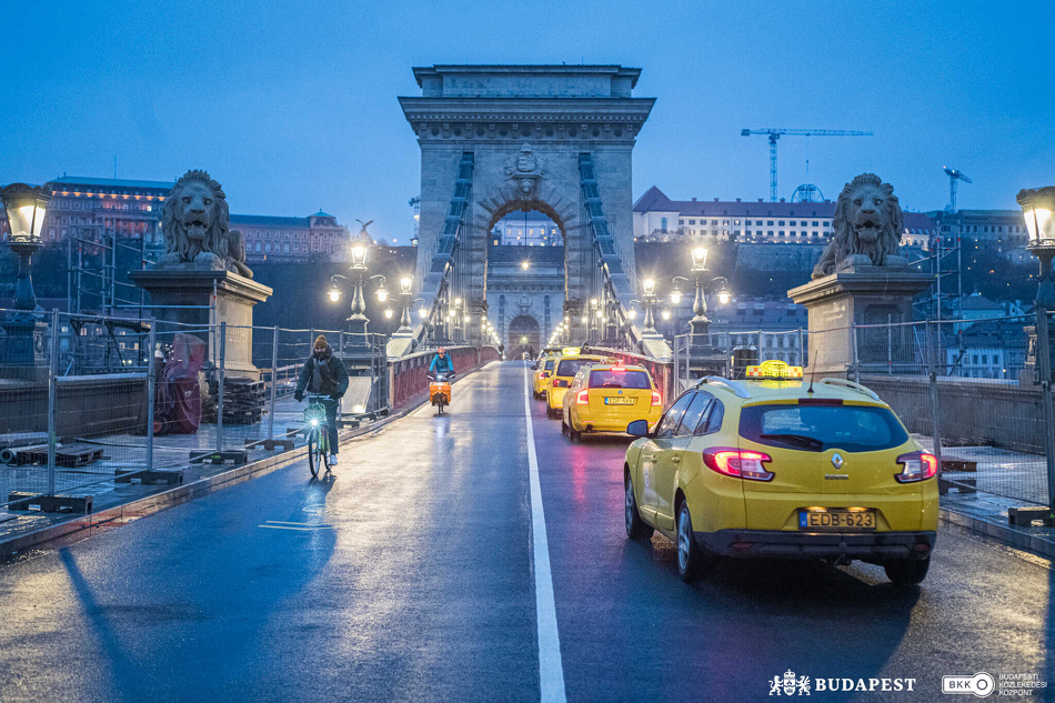 Taxik és kerékpárosok haladnak át a Lánchídon