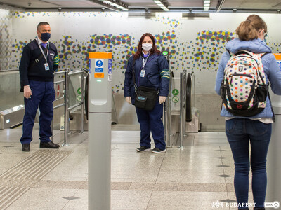 Egy utas jegyet érvényesít, a háttérben ellenőrök láthatók